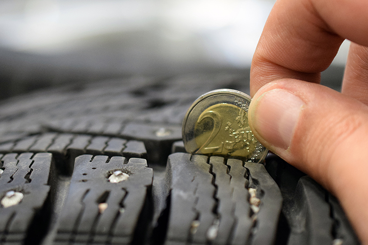 A 2 Euro coin being used to measure tred depth on a car tyre