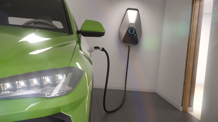Green electric car being charged by a wall charger in a home garage