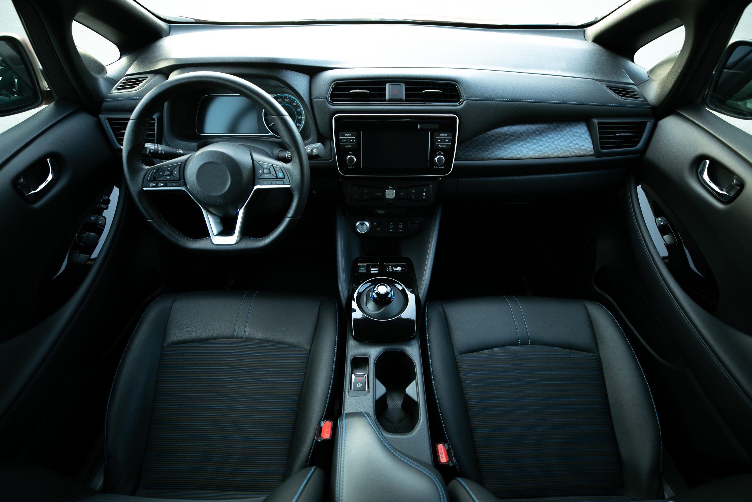 A view from the back seat of a car showing the inside of an electric vehicle. It has no traditional gearbox and just a forward, reverse and neutral setting. 