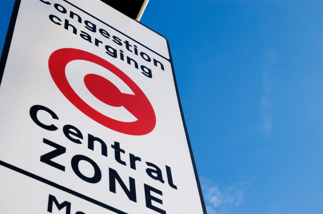 Congestion charge sign against a blue sky. Red circle with a white C on a white sign stating "Congestion charging Central Zone"