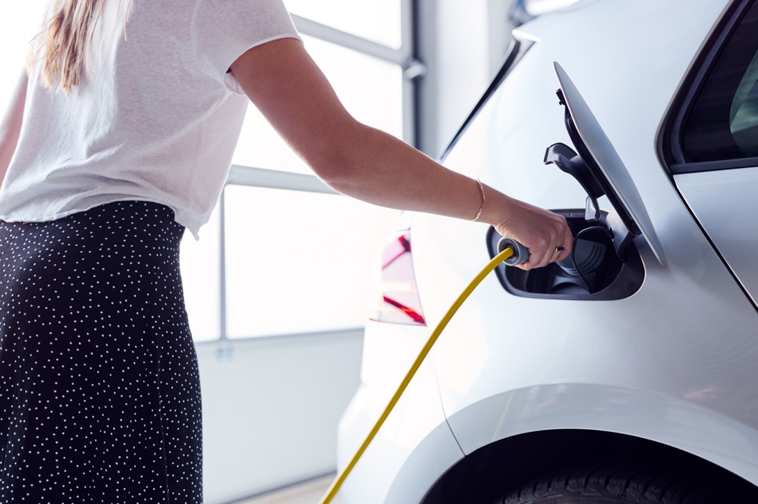 Woman Charging a white EV in Garage