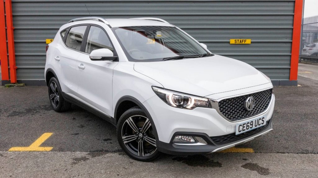 A white MG ZS EV parked in front of a garage