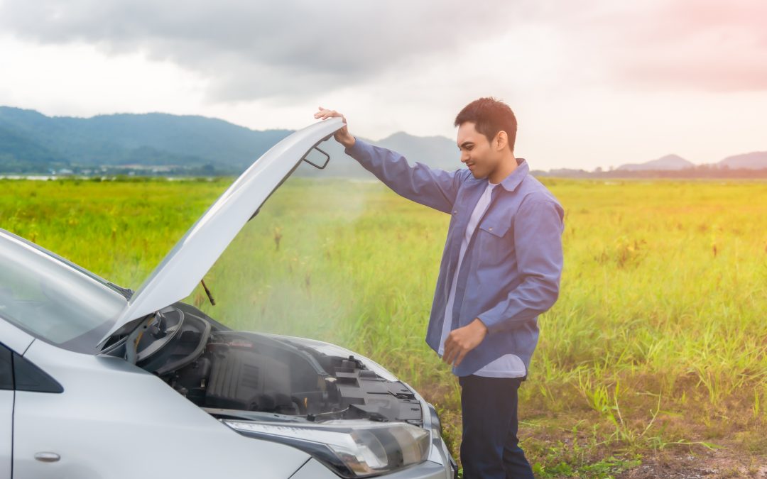 Man opening bonnet of an overheated car in the countryside