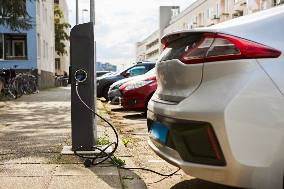 White EV plugged into road side EV charging point