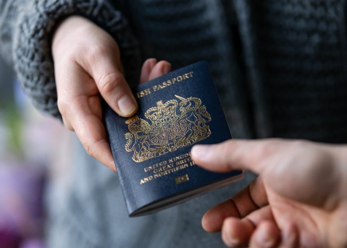 Hand passing over a navy blue British passport