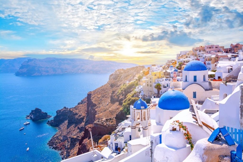 Panoramic view of blue and white Cyclades trademark buildings on Greek hill tops near the sea