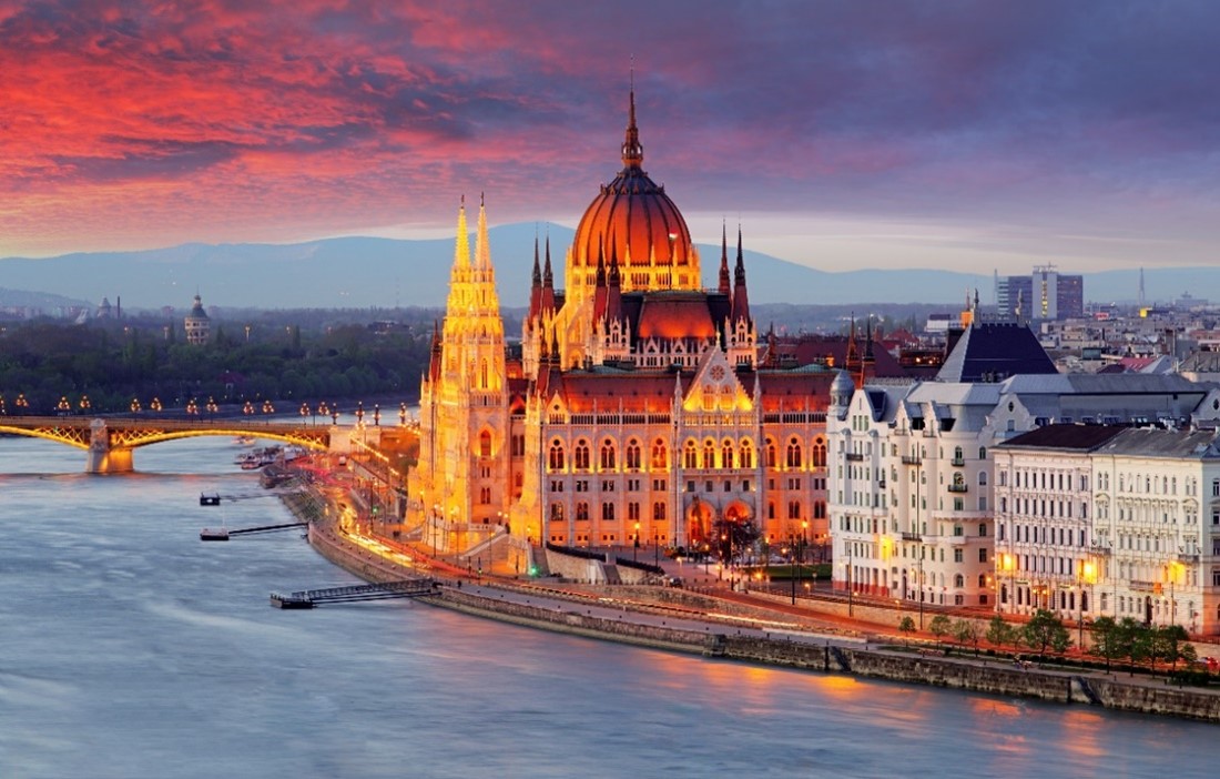 Pink sun set above Hungarian Parliament buildings situated next to river