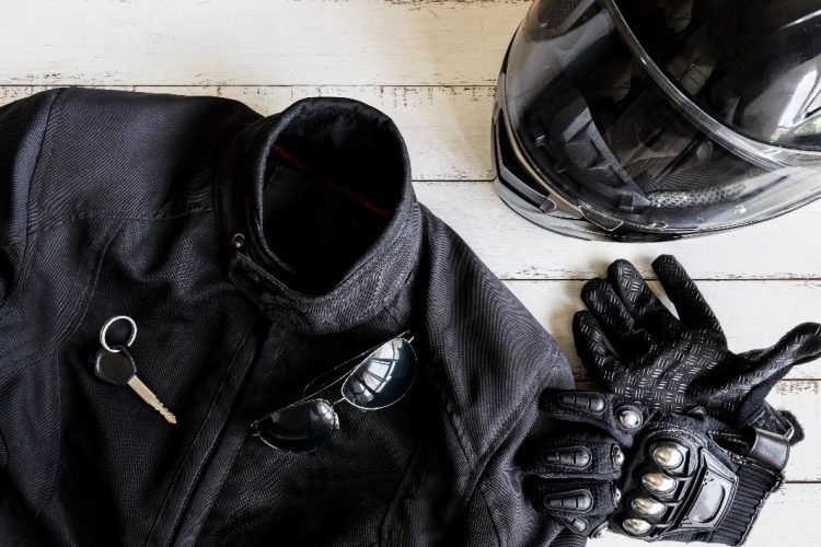 A black leather biker jacket, black biker helmet, black biker gloves, a key and a paid of sunglasses