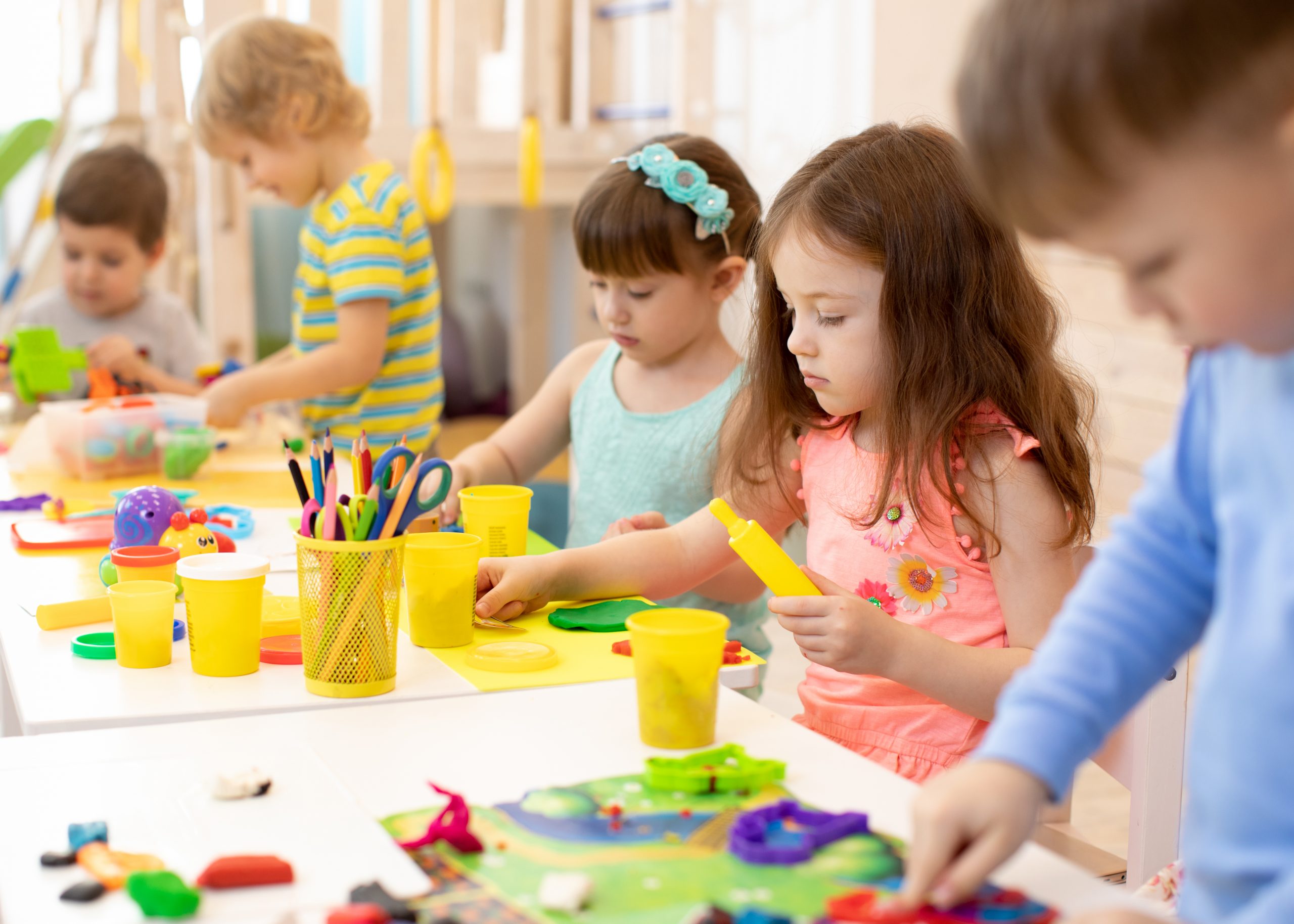 Art and craft activity in kindergarten. Group of preschool kids hands working in daycare center.