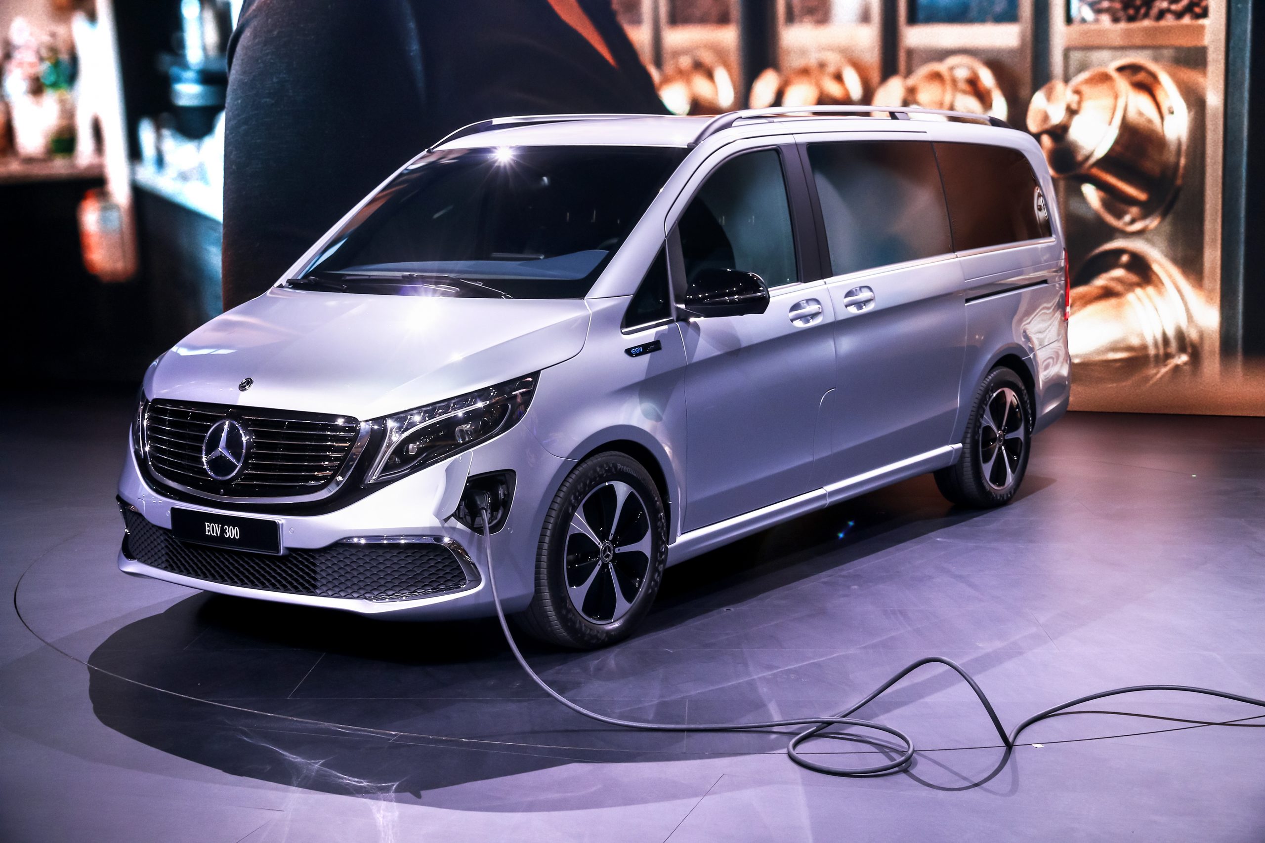 Silver mercedes EQV plugged in charging in a show room