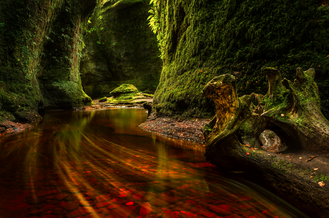 Red water running through green mossy banks at Devils Pulpit
