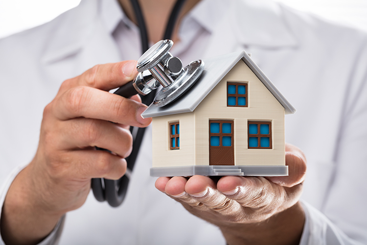 Close-up of a doctor's hand examining house model with stethoscope