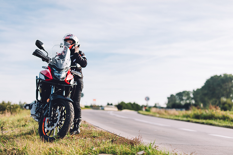 Woman preparing to drive a motorbike. Wearing helmet on a roadside