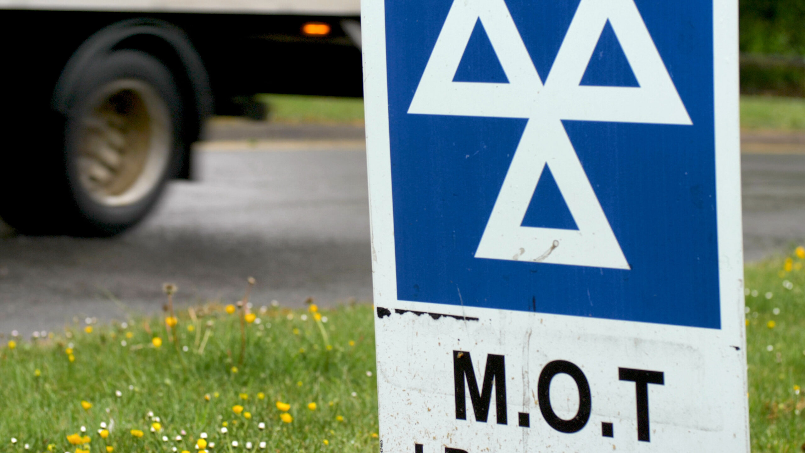 Blue MOT service sign on british road on cloudy rainy day.