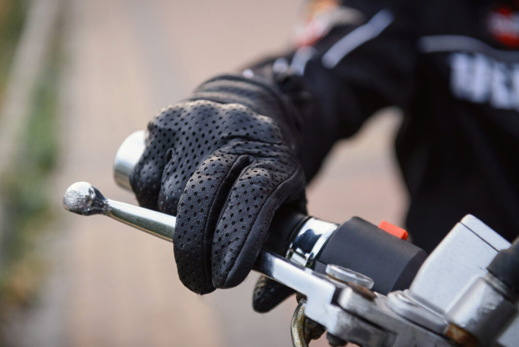 protective biker gloves on a motorcycle wheel. Driver decelerates, close-up