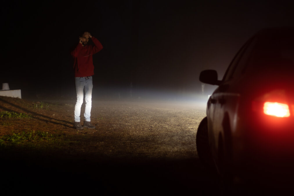 Man stood next to broken down vehicle at night