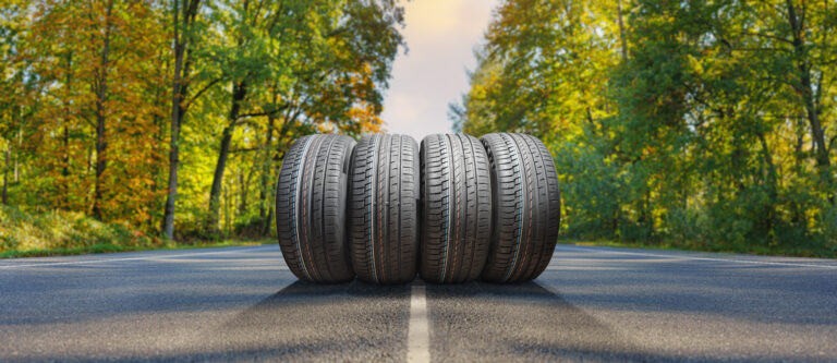 4 black tyres in the middle of a road with greenery in the background