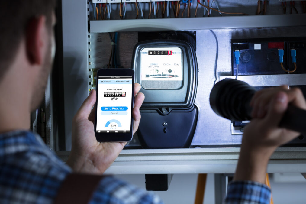 Close-up Of A Man's Hand Holding Mobile Phone Showing Electric Meter Reading And Holding Flashlight