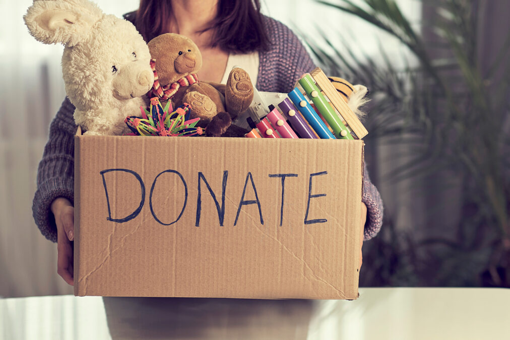 Donation box with children toys on blue background close-up