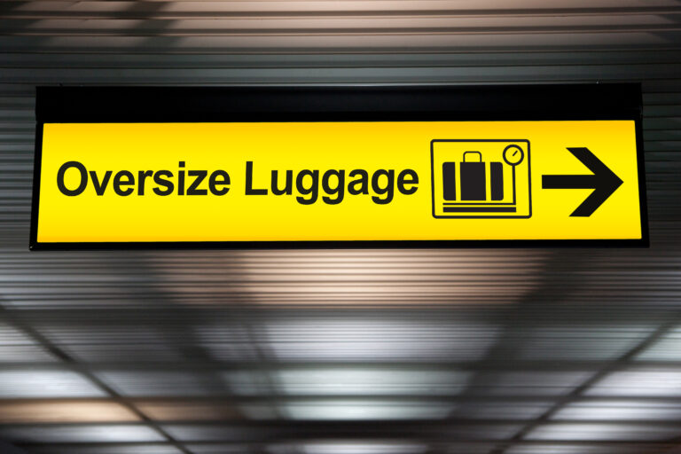 oversize luggage yellow sign with arrow direction hang from ceiling at the airport