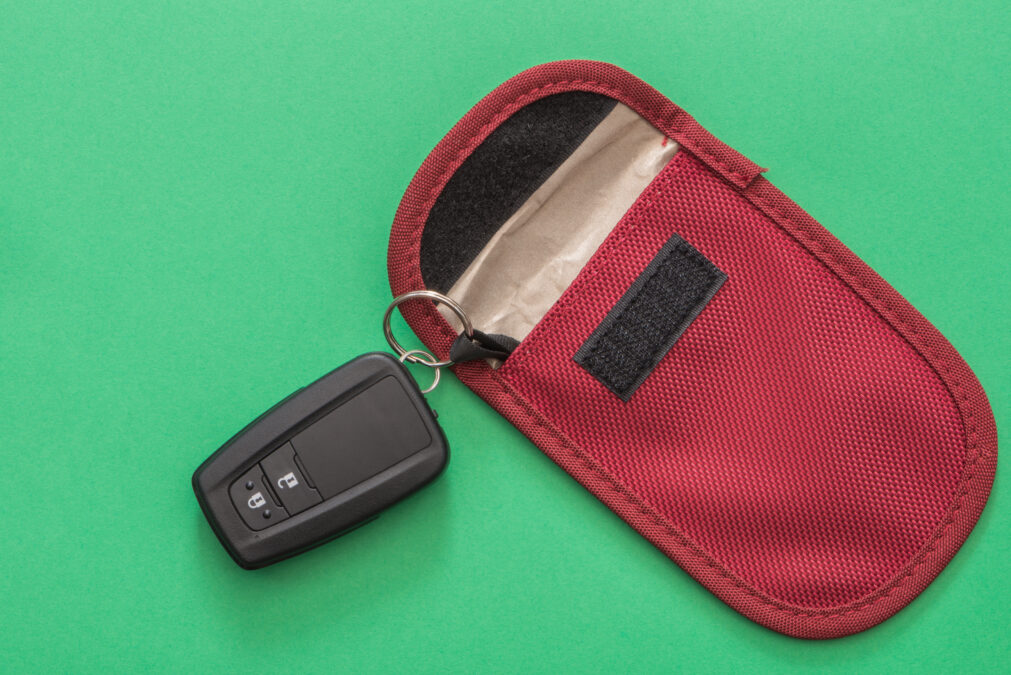 Red fabric Faraday pouch with a black car key on a green background