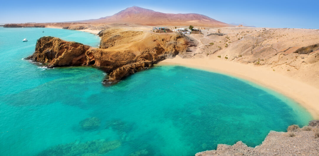 Lanzarote Papagayo turquoise beach and Ajaches in Canary Islands. Turquoise water with a sandy rock coastal background