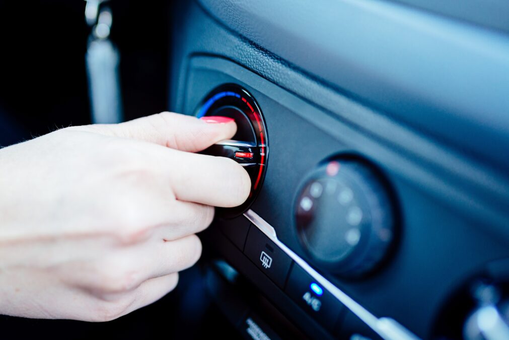 Woman regulates heating in her car. Modern car interior