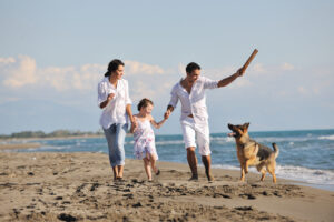 Family playing with dog on beach