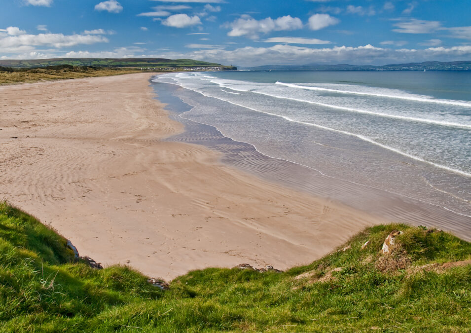 Portstewart Strand, Coleraine, Ireland - on a bright sunny day. Green foreground looking down on a sandy beach with blue