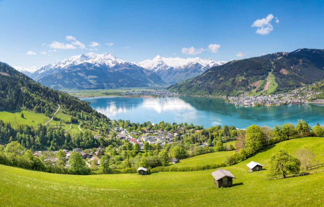 View over Zell am See in Summer, Salzburg, Austria. A green foreground in front of a large lake surrounded by mountains 