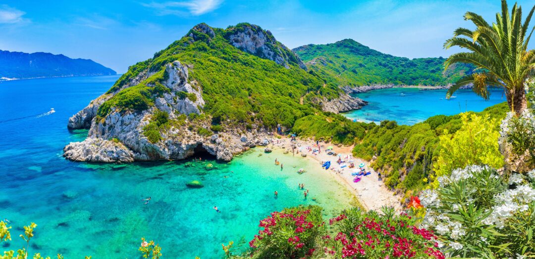 View of small beach in Corfu with Crystal blue waters and a green rocky hillside