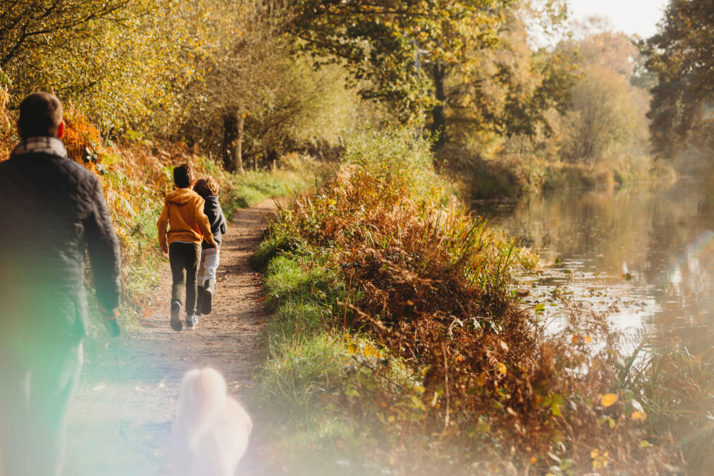 Family and dog walking along a canal on an autumn day