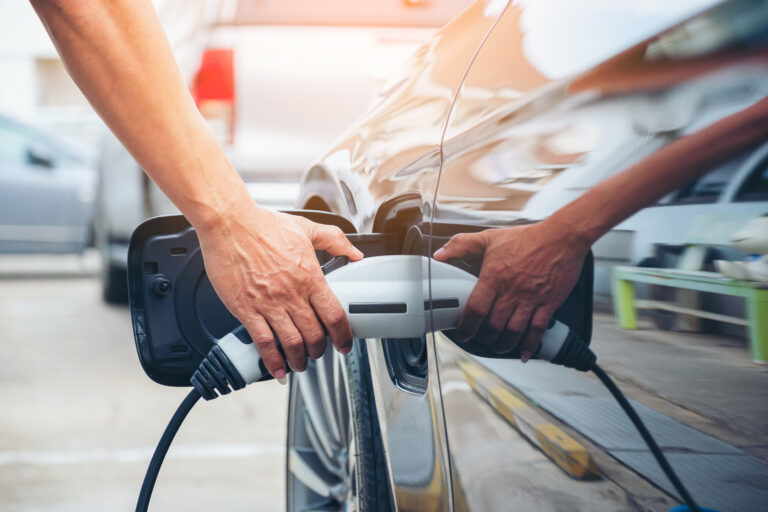 Hand hold of charging modern electric car battery on the street