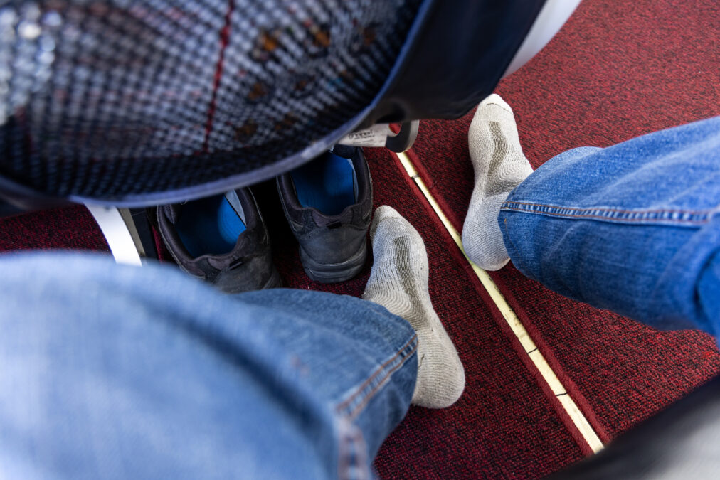 Seated aIrplane passenger removed shoes in cabin to relax feet during long haul flight