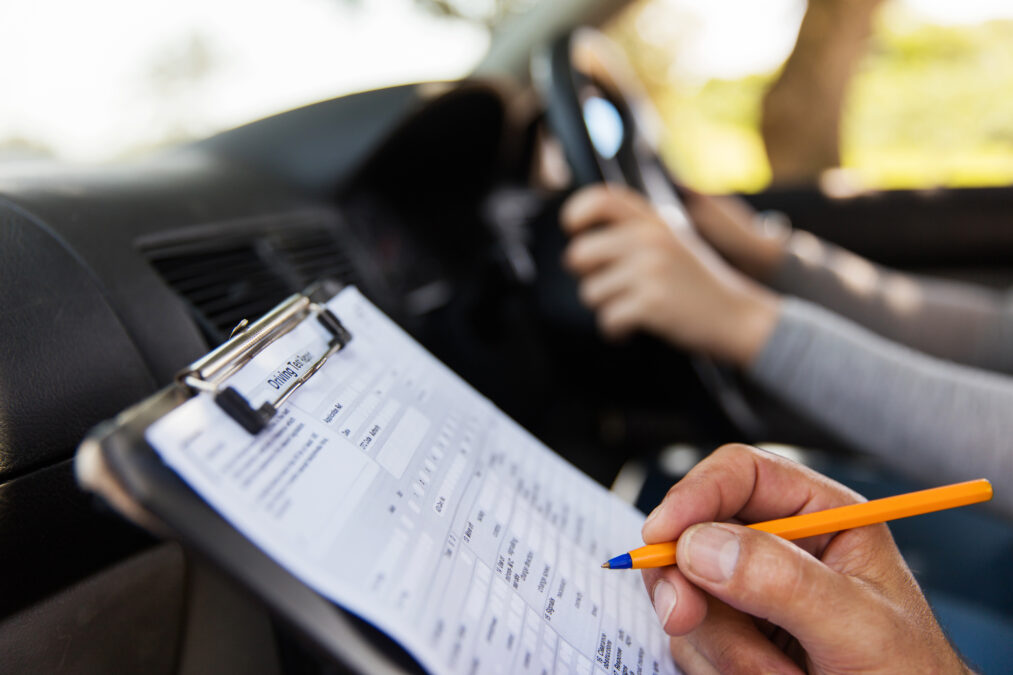 Someone marking a driving test with a pen and clipboard