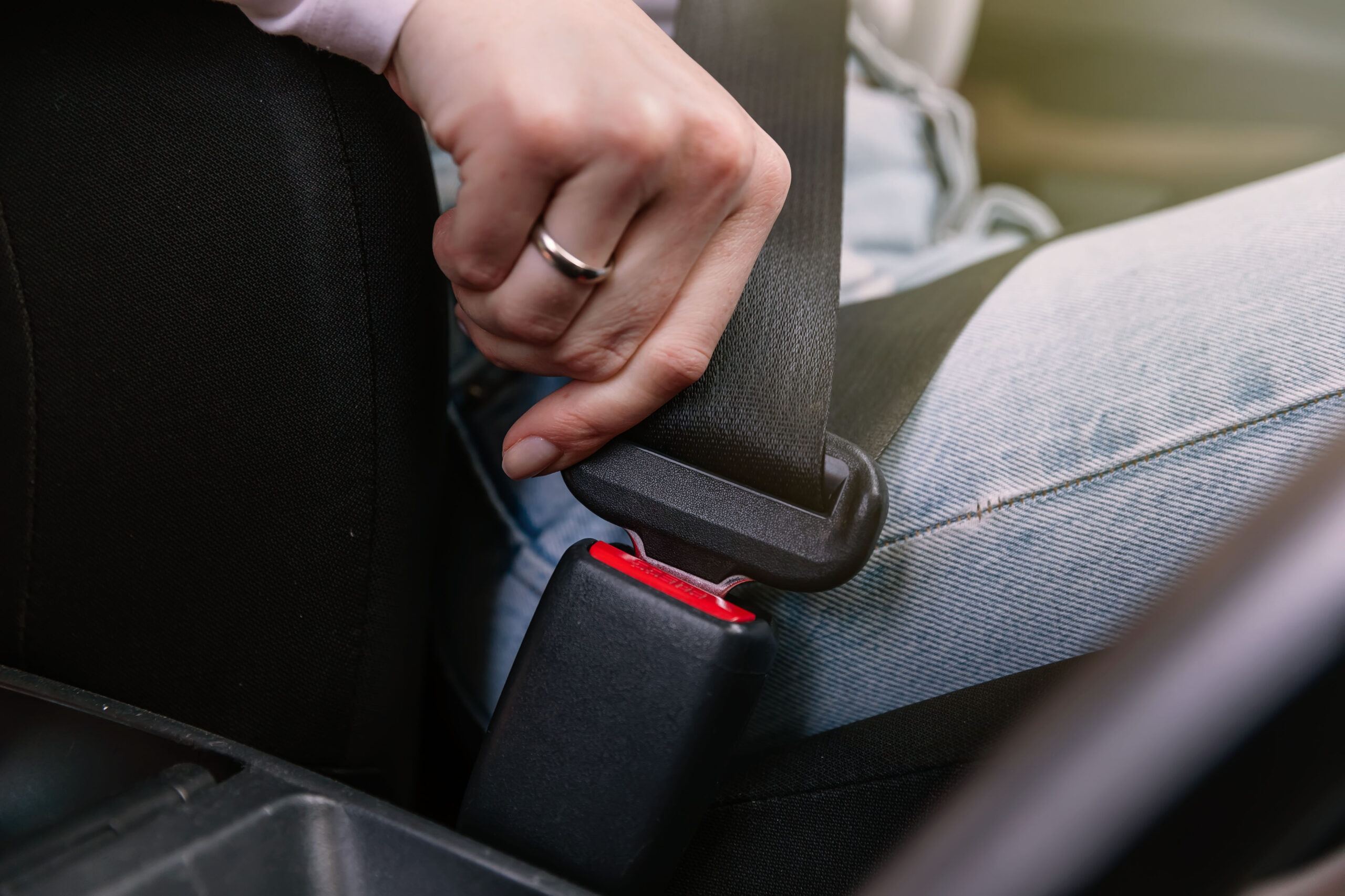 Close up image of business woman sitting in a car putting on her seat belt
