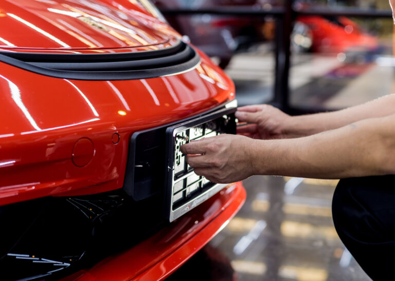 Technician changing car plate number in service center. Light background